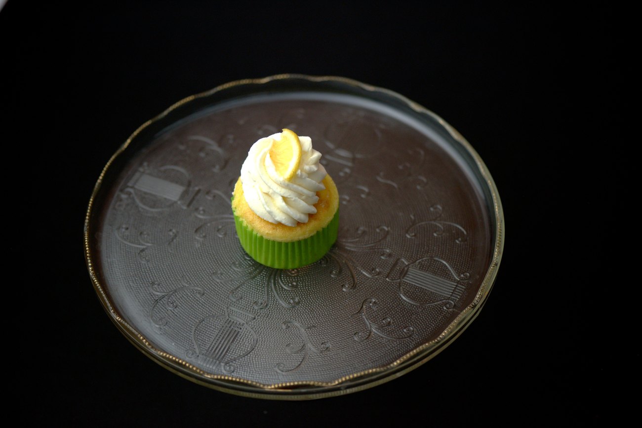 Lemon cupcake topped with a swirl of frosting and a lemon slice