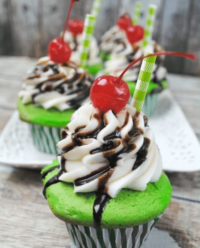 Green shake cupcakes with chocolate drizzle, a cherry, and a paper straw